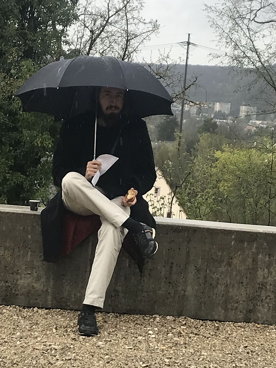 Leo sitzt mit Schirm im Regen, Pause zwischen den Vorträgen am Studientag