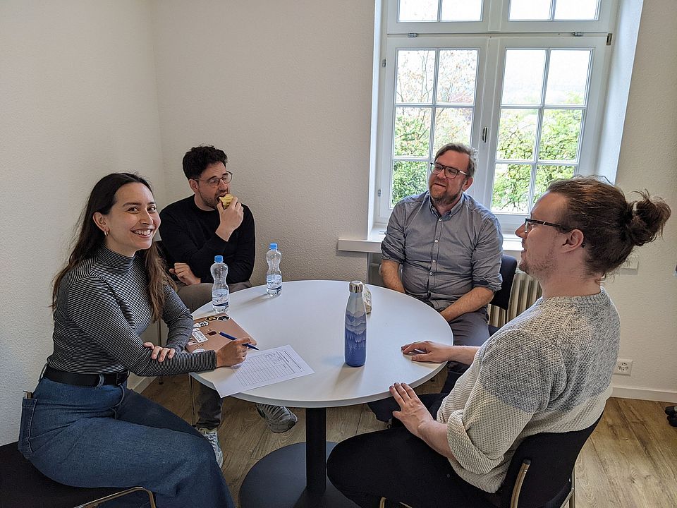 Studierende in angeregter Diskussion rund um einen kleinen Tisch