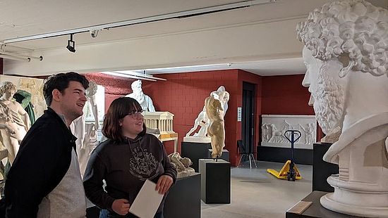 Studenten des Proseminars betrachten eine antike Skulptur
