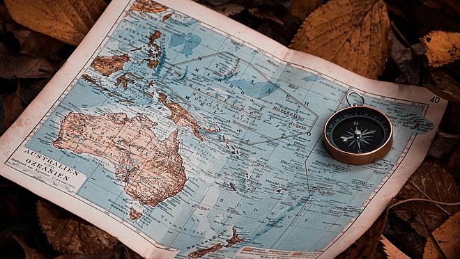 eine Karte von Ozeanien und Australien und ein alter Kompass vermitteln Reise und Aufbruch, aber auch Orientierung