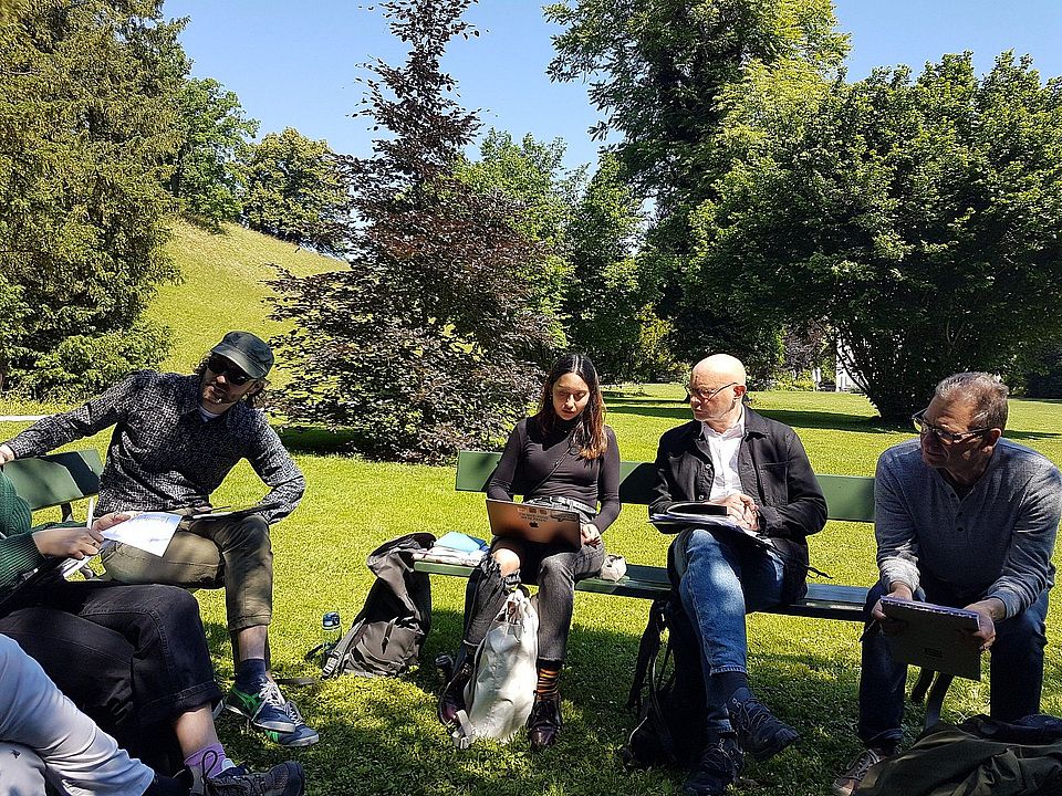 Studierende in der Sonne in den Meriangärten, sitzen in einer Runde und diskutieren