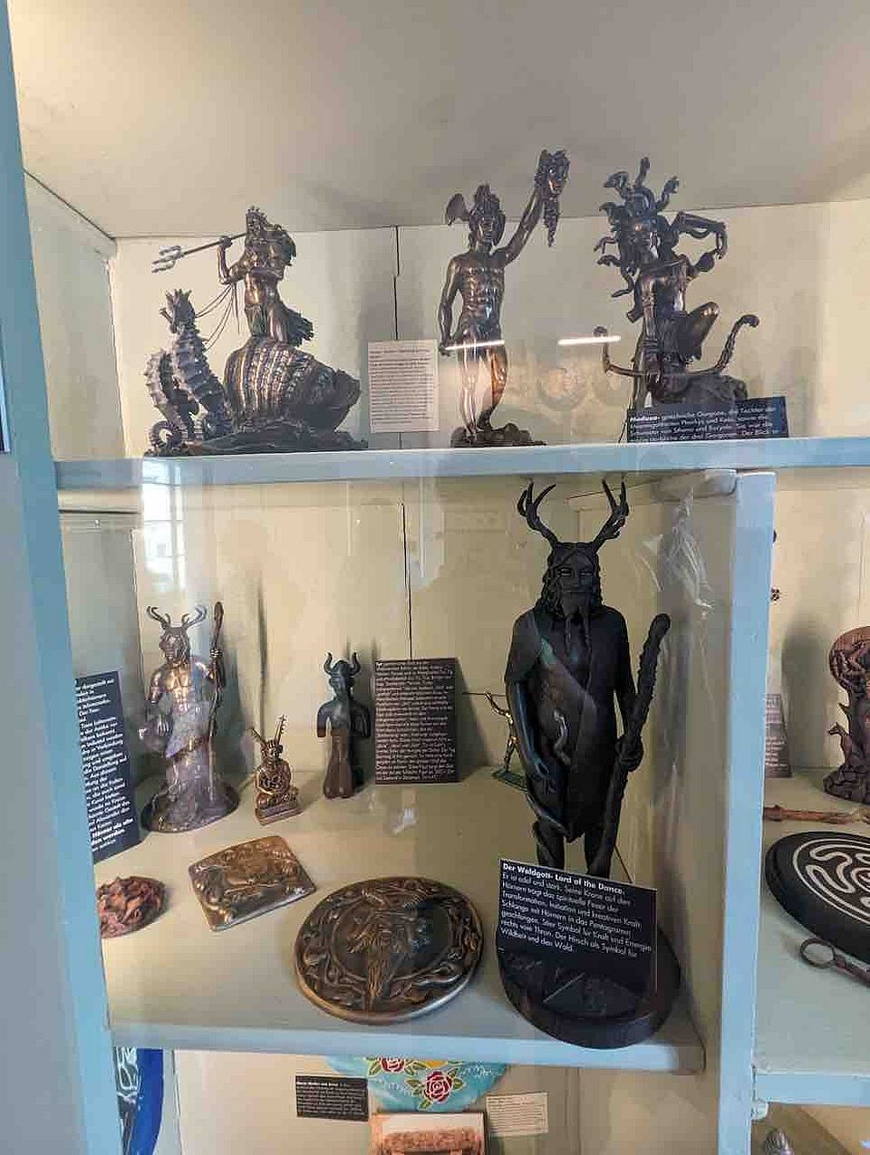 verschiedene Figuren männlicher Götter in einer Vitrine, teils beruhen sie auf historischen Darstellungen, teils sind es zeitgenössische Interpretationen